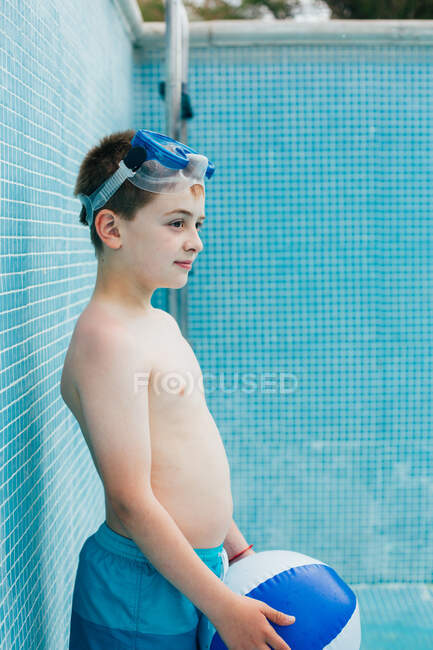 Хлопчик з м'ячем стоїть у порожньому басейні — стокове фото