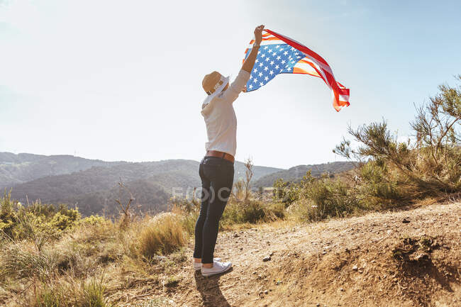 Молодая девушка празднует 4 июля с американским флагом на закате — стоковое фото