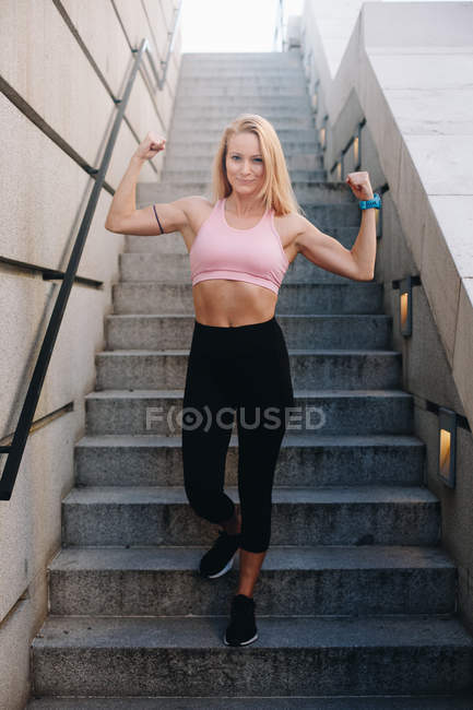 Junge blonde kaukasische Frau lässt Muskeln mit Sportbekleidung im Freien spielen — Stockfoto