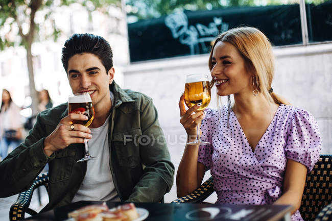 Alegre joven atractiva pareja disfrutando de bebidas refrescantes durante la fecha de la ciudad - foto de stock