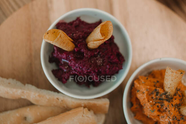 From above orange red vegetable dips with crispy crunchy bread in bowl on round stand on table — Stock Photo