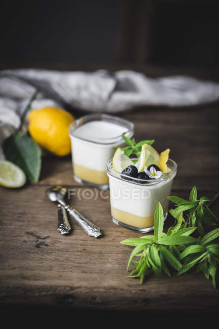 Gläser mit hausgemachtem Joghurt und Zitronenquark auf Holzoberfläche — Stockfoto
