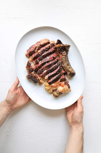 Mani con carne affettata su piatto bianco — Foto stock