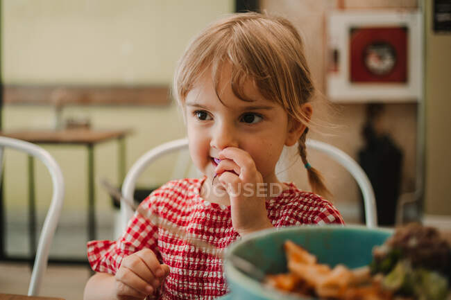 Appetizing comida variada fragrante em tigela azul e menina adorável comer à mesa — Fotografia de Stock