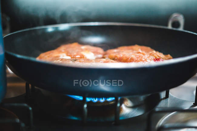Closeup deliciosas costeletas de carne fritar em óleo na panela quente na cozinha — Fotografia de Stock