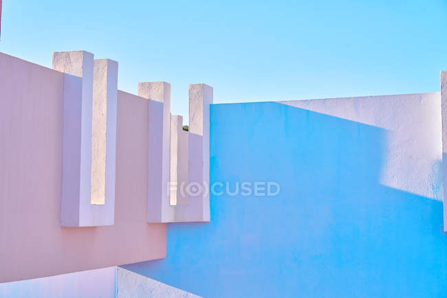 Edificio rosa de forma geométrica compleja bajo el cielo azul - foto de stock