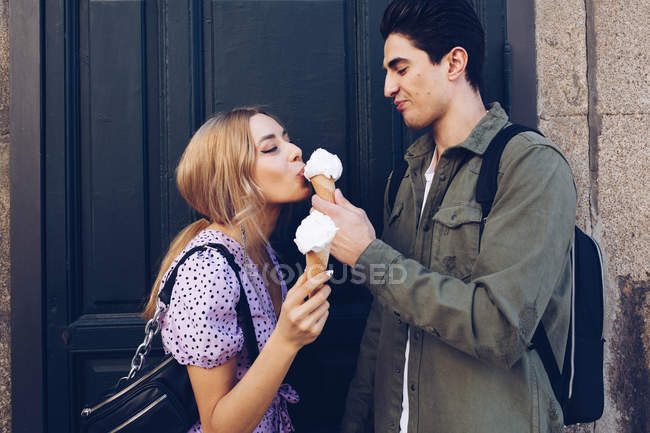 Cheerful young attractive woman and boyfriend eating ice cream outdoors — Stock Photo