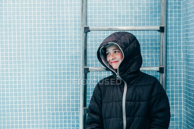 Niño en ropa de abrigo de pie en la piscina vacía - foto de stock