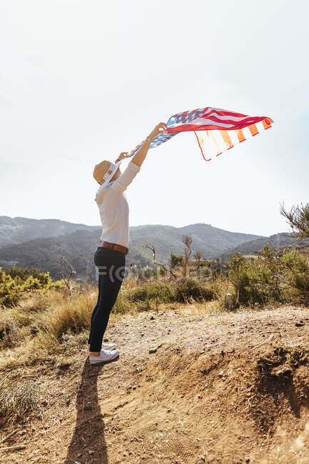 Jeune fille célébrant le 4 juillet avec un drapeau américain au coucher du soleil — Photo de stock
