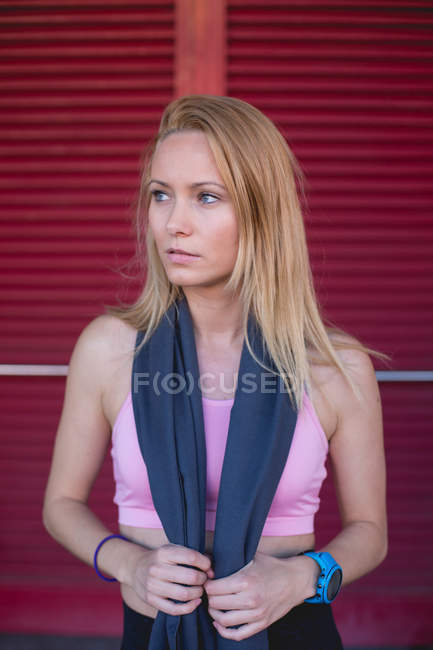Jovem loira caucasiana tendo um descanso de uma sessão de corrida com toalha embrulhada no pescoço — Fotografia de Stock