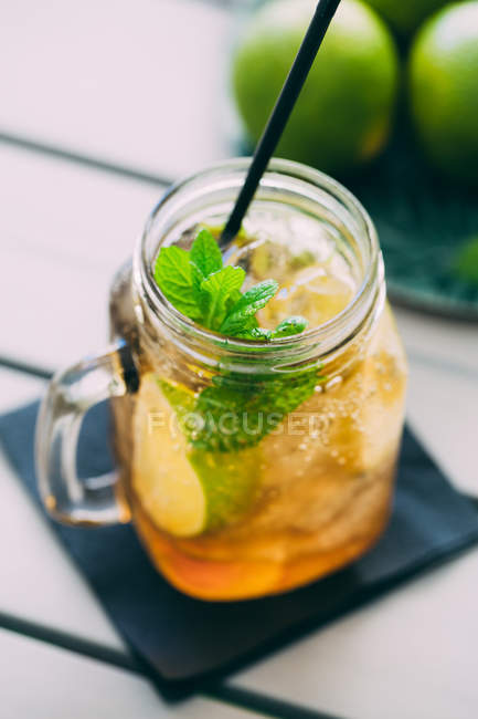 Coquetel de mojito preparado com limão, hortelã, rum, refrigerante e gelo em pote de pedreiro na mesa — Fotografia de Stock