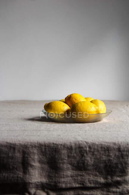 Спелые сочные лимоны в тарелке на столе — стоковое фото