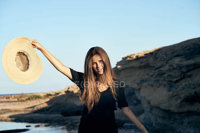 Young smiling woman looking away on rocky coast — Stock Photo