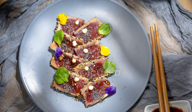 Do acima mencionado delicioso apetitoso pedaços de atum tataki fresco com folhas verdes no prato — Fotografia de Stock