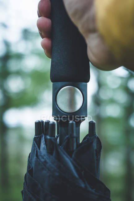 Крупним планом рука людини з ручкою натискання на кнопку парасольки для відкритої парасольки на розмитому фоні — стокове фото