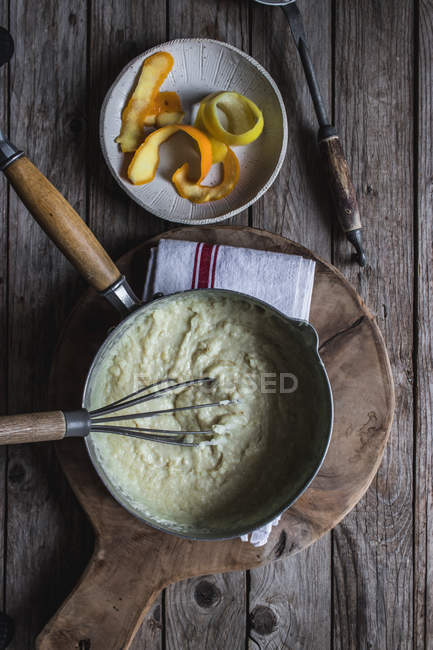 Von oben Auflaufform mit Teig zum Kochen von Kuchen auf Schneidebrett mit Eiern auf Holztisch — Stockfoto