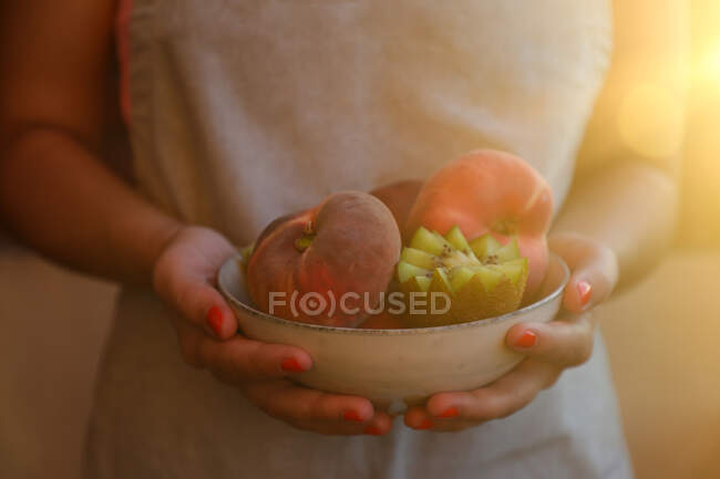 Ripe peaches and cut kiwi in bowl — Stock Photo