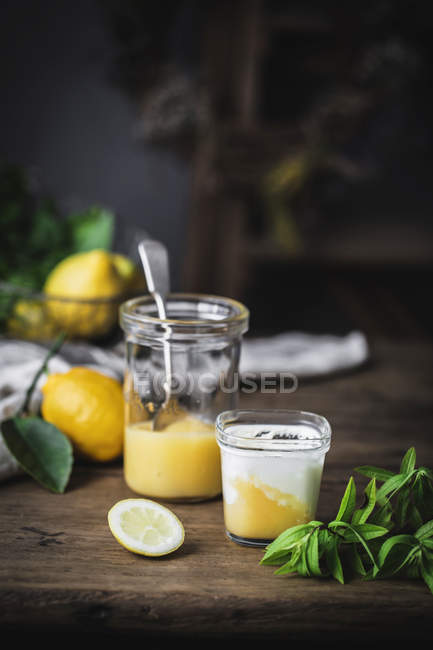 Vidro de iogurte caseiro e coalhada de limão na superfície de madeira — Fotografia de Stock