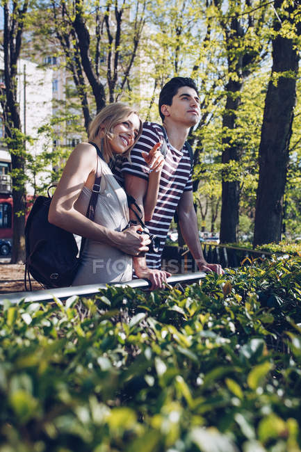 Atractiva pareja joven de turistas admirando la vista mientras están de pie en el parque - foto de stock