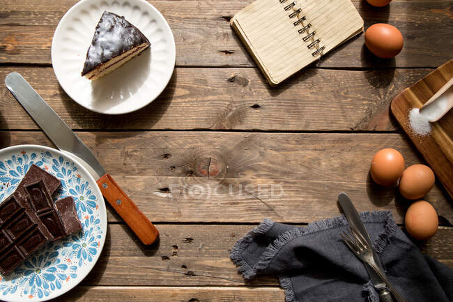 Eggs chocolate slice of cake and notebook on table — Stock Photo