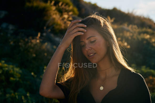 Ritratto di giovane donna in piedi nella natura nella soleggiata giornata estiva — Foto stock
