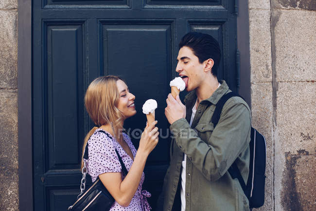 Joyeux jeune femme attrayante et petit ami manger de la crème glacée à l'extérieur — Photo de stock