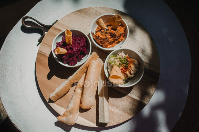 From above orange red vegetable dips with crispy crunchy bread in bowl on round stand on table — Stock Photo