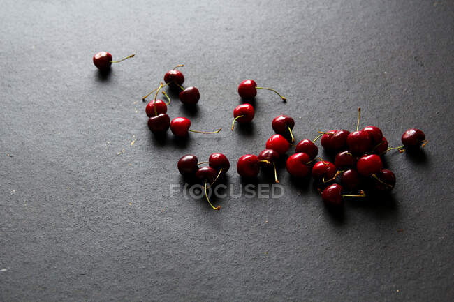 Блискучі стиглі червоні вишні на чорному тлі — стокове фото