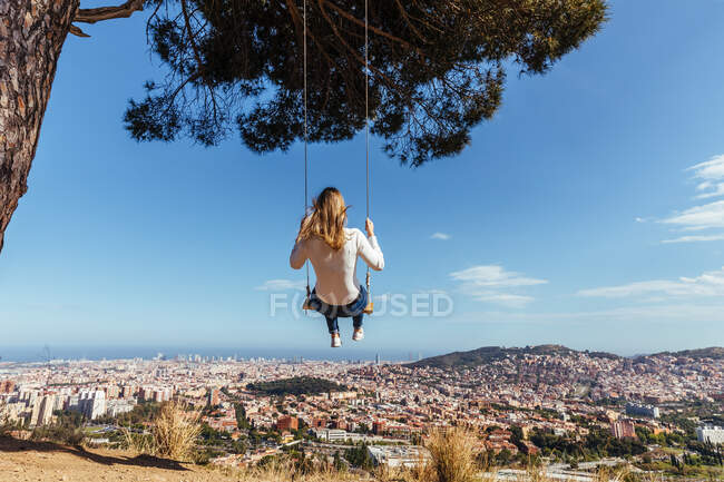Blondes Mädchen schwingt mit Blick auf die Stadt im Hintergrund — Stockfoto