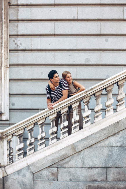Atractiva pareja admirando la vista mientras está de pie en las viejas escaleras del edificio histórico - foto de stock