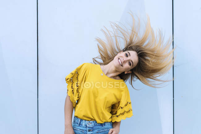 Junge fröhliche Frau schüttelt die Haare und lächelt in die Kamera — Stockfoto