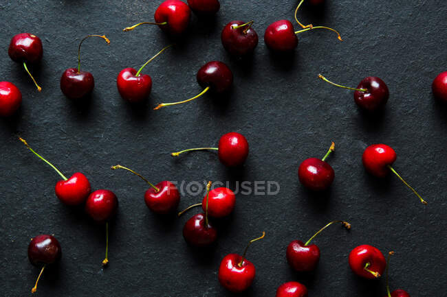 Блестящие спелые красные вишни на черном фоне — стоковое фото
