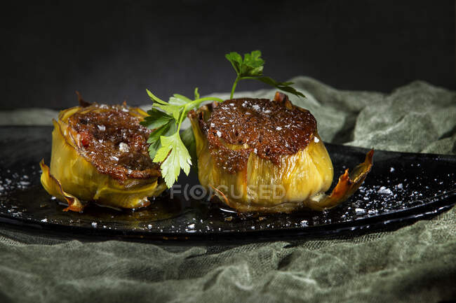 Tasty stuffed artichokes with salt on black background — Stock Photo