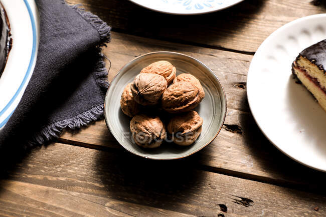 Nuts in bowl cake and napkin on table — Stock Photo