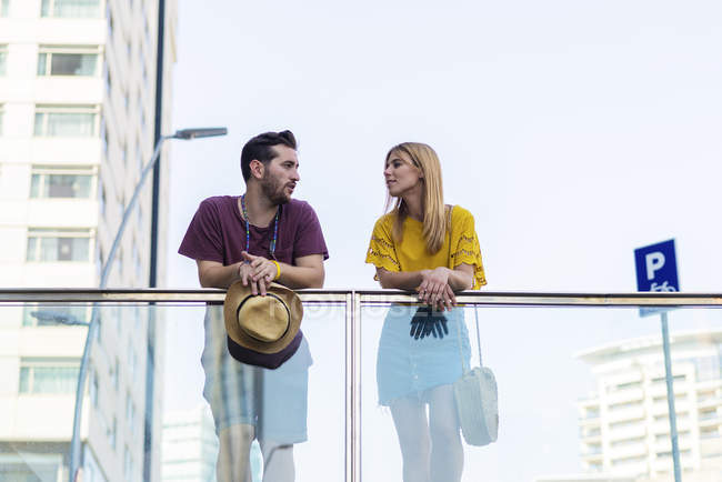 Jovem casal elegante olhando uns para os outros na ponte na cidade — Fotografia de Stock