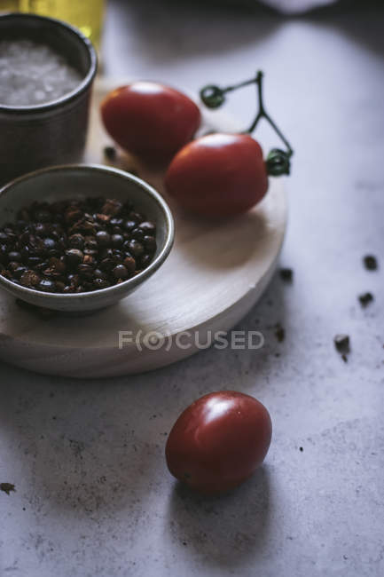 Крупный план перца и соли со свежими помидорами на деревянной доске — стоковое фото