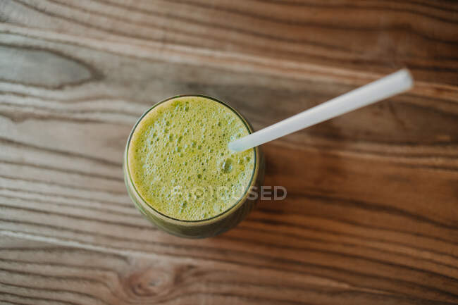 From above bubble frothy tasty fragrant green smoothie in glass on wooden table — Stock Photo
