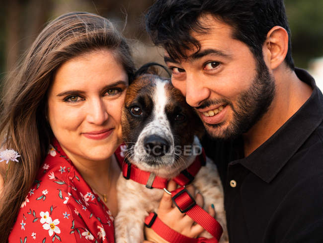 Sorridente coppia che tiene simpatico cagnolino in campagna — Foto stock