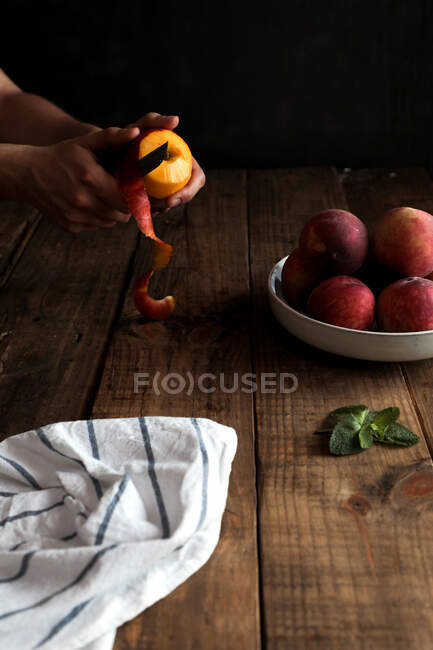 Вкусные спелые персики в тарелке и ручная чистка персика — стоковое фото