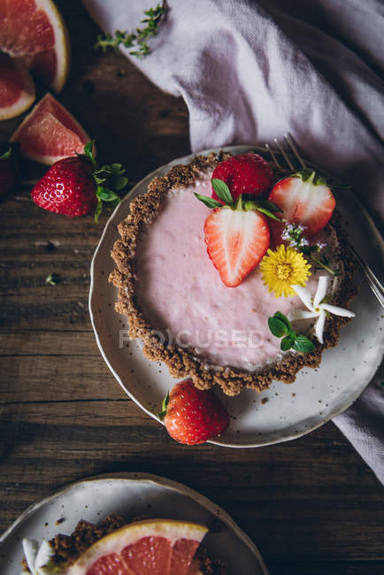 Blick von oben auf die Portion köstlicher Erdbeer- und Zitruskuchen, serviert auf dekoriertem Holztisch — Stockfoto