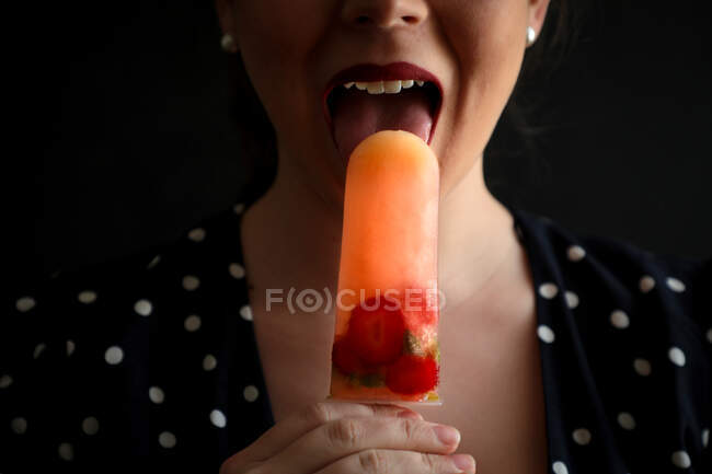 Mujer comiendo paleta de frutas con bayas - foto de stock