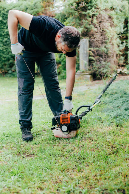 Caucasian man switching on and trimming an arizonica hedge with mechanical tools — Stock Photo