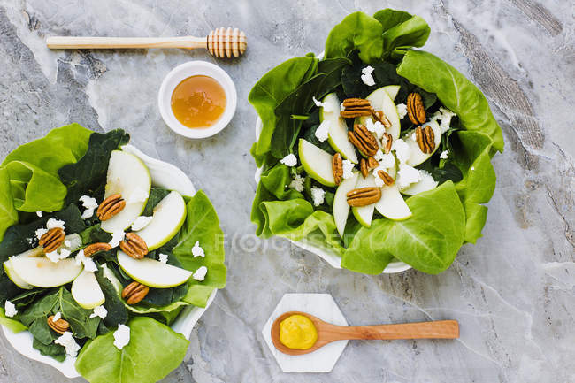 Served bowls with cut pears and pecans on table with honey — Stock Photo