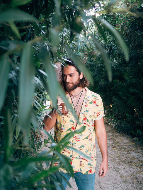 Pensivo homem hipster barbudo andando na selva com ukulele — Fotografia de Stock