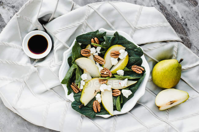 Served bowl with cut pears and pecans on table with soy sauce — Stock Photo