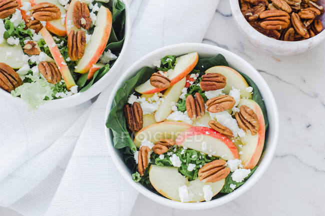 Served bowls with cut apples and pecans salad on table — Stock Photo
