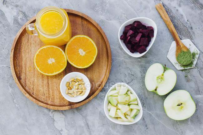 Des oranges, arachides et jus d'orange servis sur la table avec des pommes, des condiments et un bol de betterave — Photo de stock