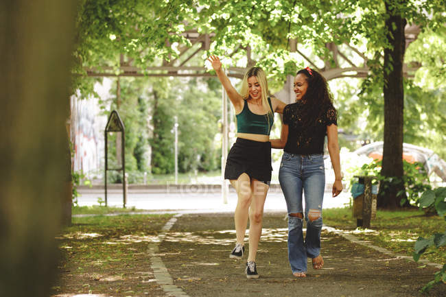Femmes de bonne humeur marchant dans une rue verte de Berlin par une journée ensoleillée — Photo de stock