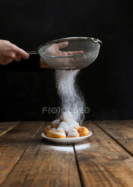 Persona che spruzza zucchero a velo sui biscotti — Foto stock