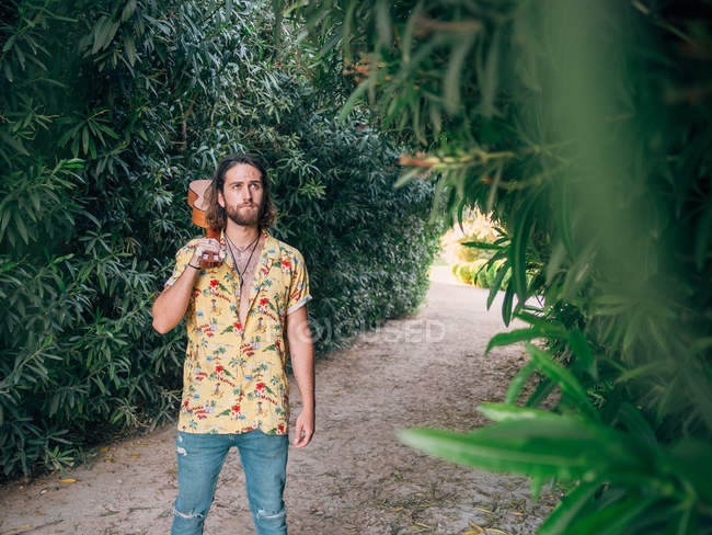 Uomo hipster barbuto pensieroso che cammina nella giungla con ukulele — Foto stock